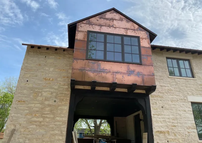 Copper metal panel facade on a stone building for Skylight Installation in Ames