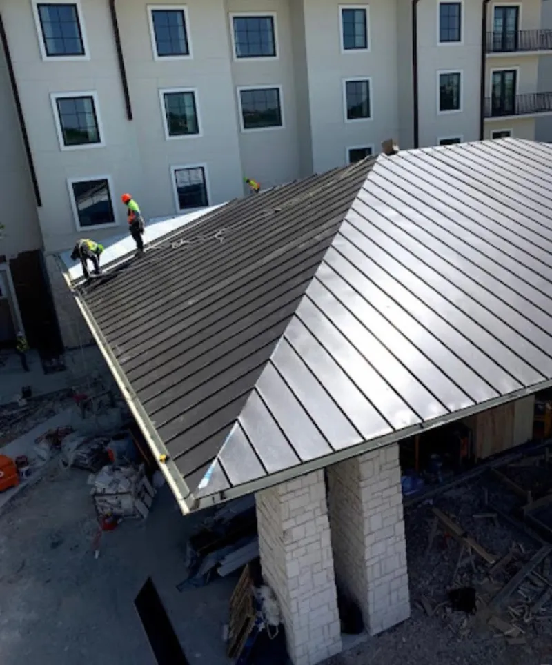 Crew installing standing seam metal roof panels on a commercial project in Ames